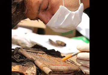 Dusting off a cane box with gold weaving tools
