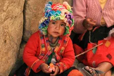 Niña sentada en la calle del Cusco junto a su madre