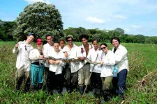Group holding large boa snake in the marshlands of Bolivia.