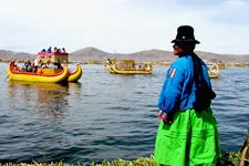 Woman looking over Lake Titicaca at reed boats of Uros near 
